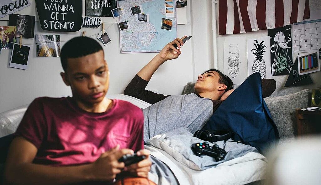Leitlinie Exzessive Mediennutzung Computerspielsucht Junge mit Smartphone und Junge mit Controller