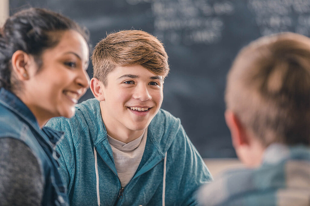 Informationen zu den Net-Piloten für Lehrkräfte Drei Jugendliche diskutieren gemeinsam im Klassenzimmer.