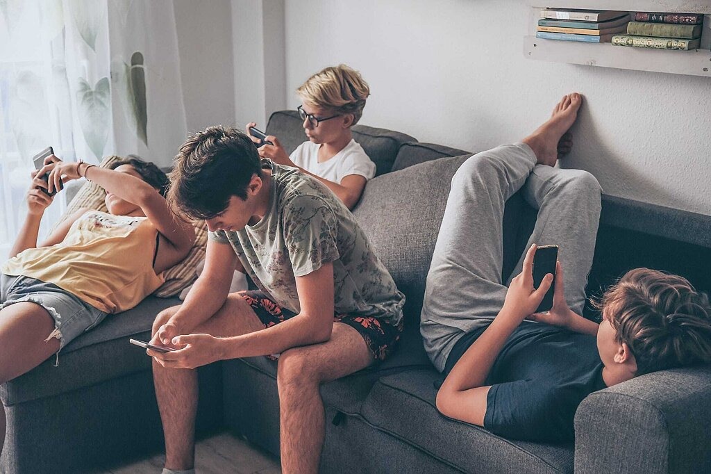 DAK Studie Mediensucht Jugendliche Jugendliche liegen und sitzen auf Sofa mit Smartphones