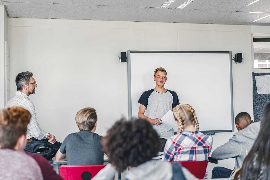 Referats- und Diskussionsthemen für den Unterricht zum Thema digitale Mediennutzung Jugendlicher hält einen Vortrag vor seiner Klasse.