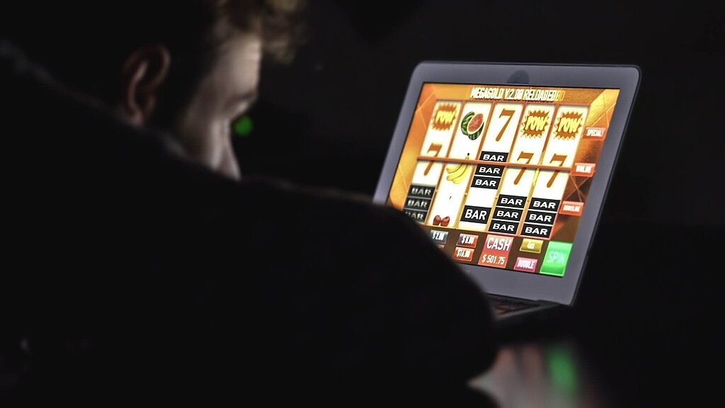 Junger Mann spielt an einem digitalen Spieleautomaten in einem dunklen Zimmer. Junger Mann spielt an einem digitalen Spieleautomaten in einem dunklen Zimmer.