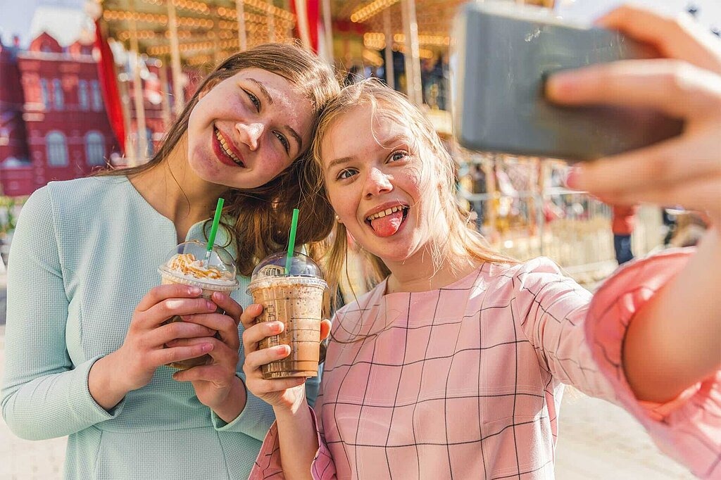 Soziale Netzwerke im Überblick Zwei Mädchen machen ein Selfie mit Milchshake in der Hand.