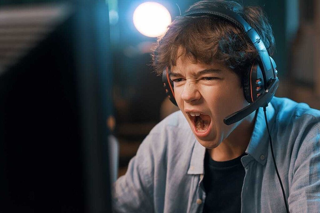Jugendschutz Junge schreit in Headset vor Computer