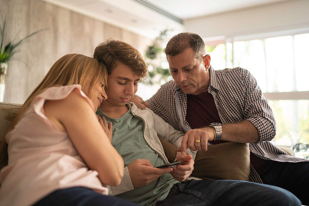 Handyregeln - Internetsicherheit für Jugendliche Eltern schauen mit Sohn zusammen auf Smartphone