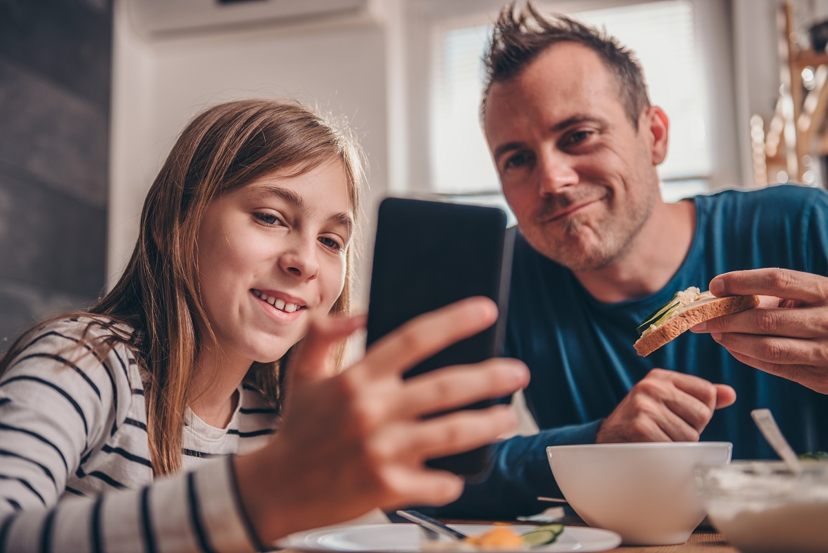 Tochter zeigt Vater etwas auf Smartphone