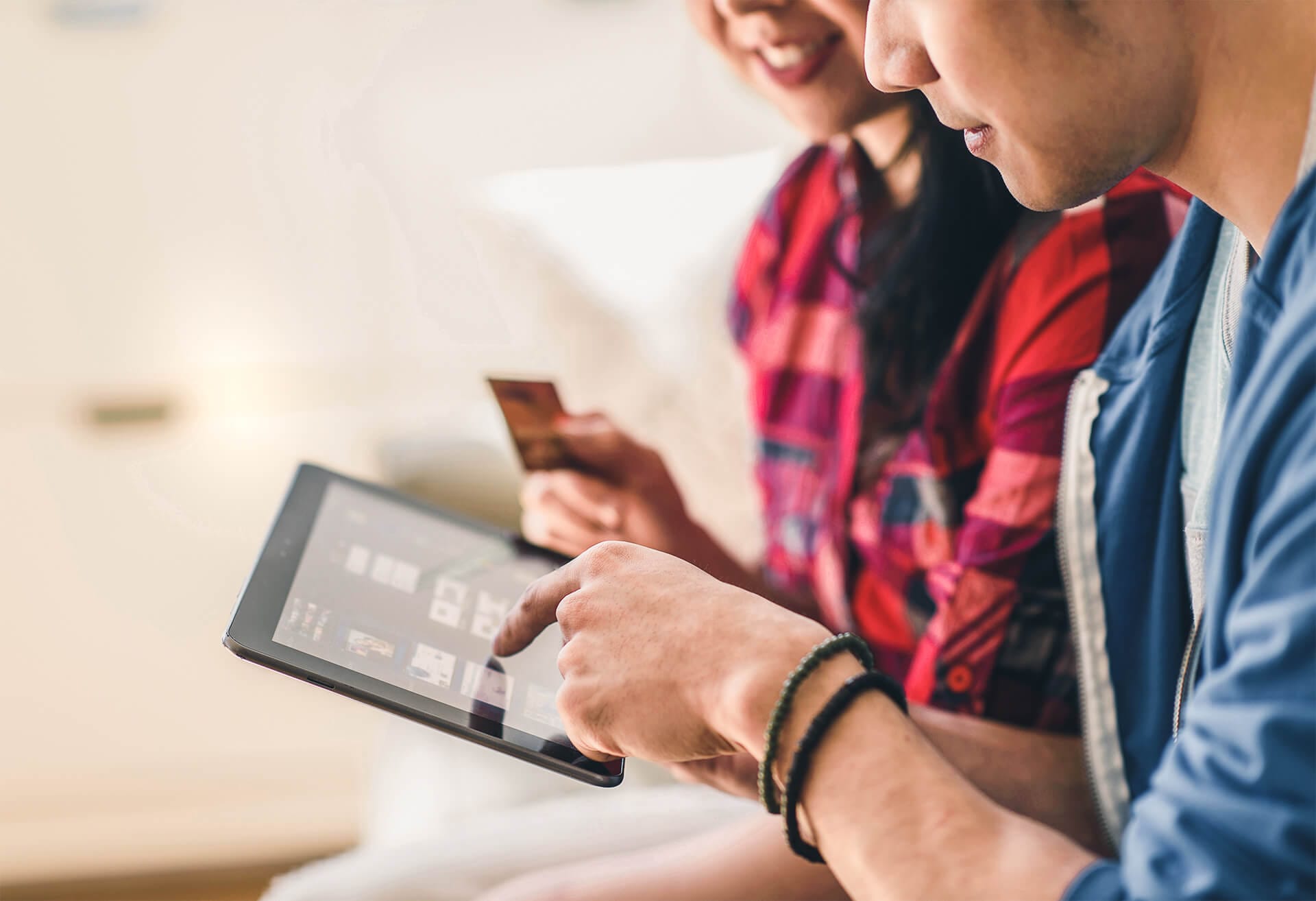 Zwei Personen halten Tablet und Kreditkarte in Hand.