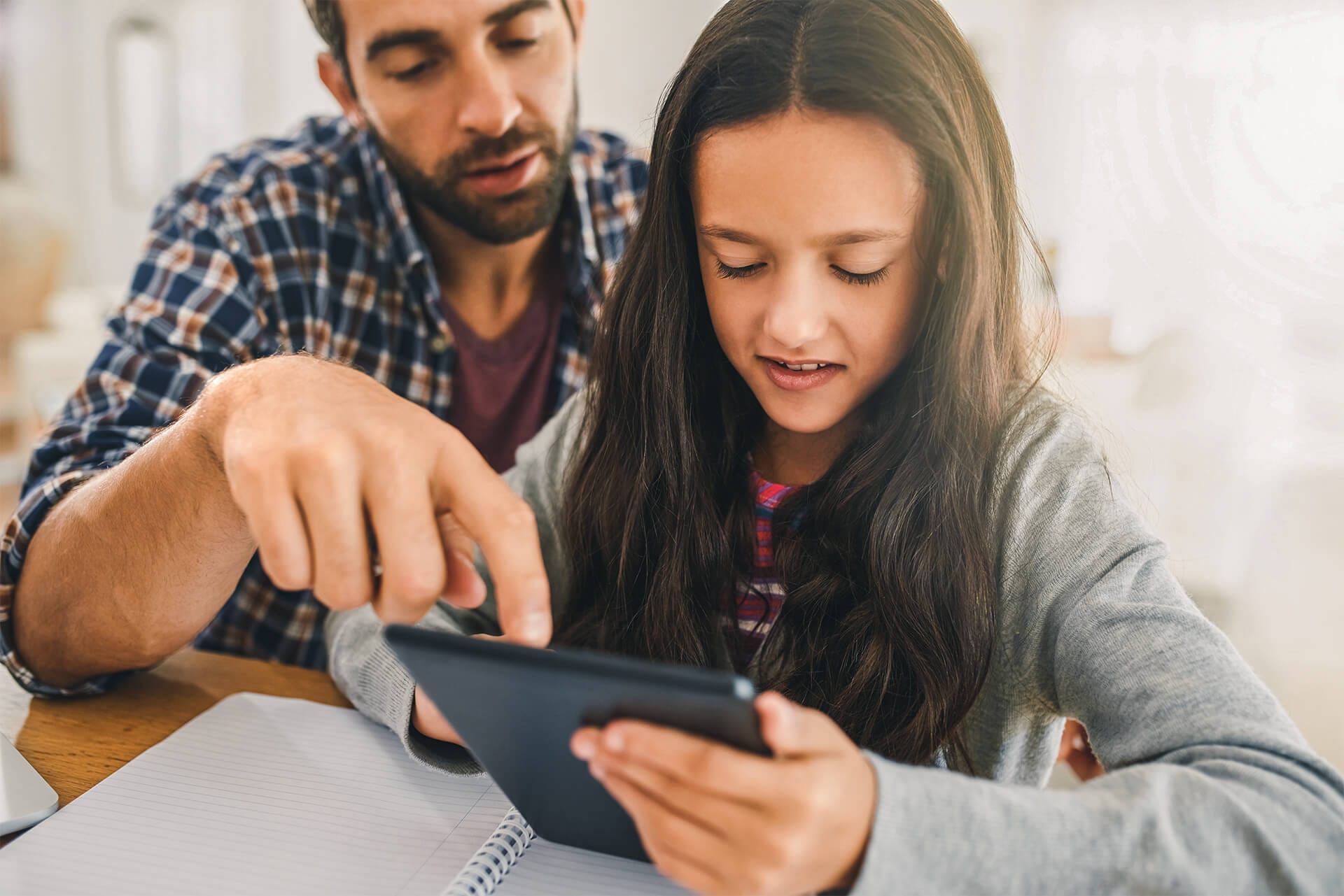 Vater erklärt Tochter etwas an Tablet