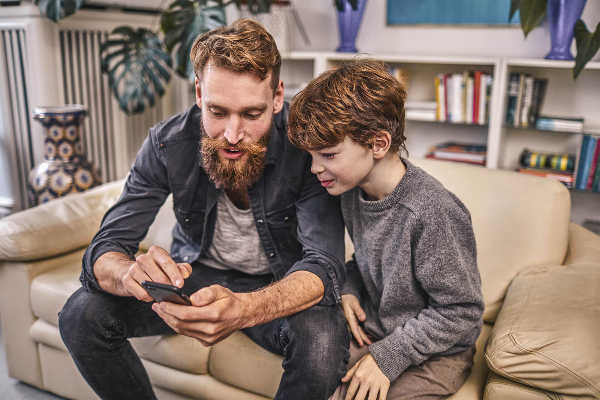 Vater zeigt seinem Sohn etwas auf seinem Smartphone.