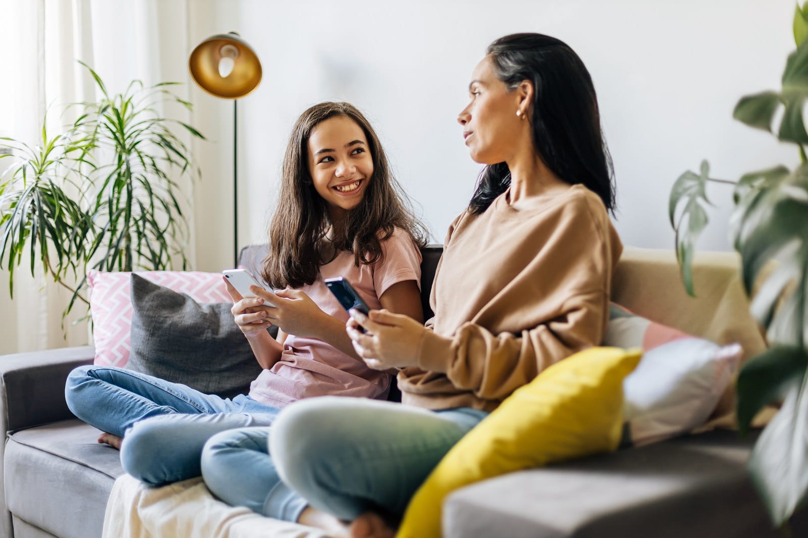 Mutter und Tochte mit Smartphones auf Sofa