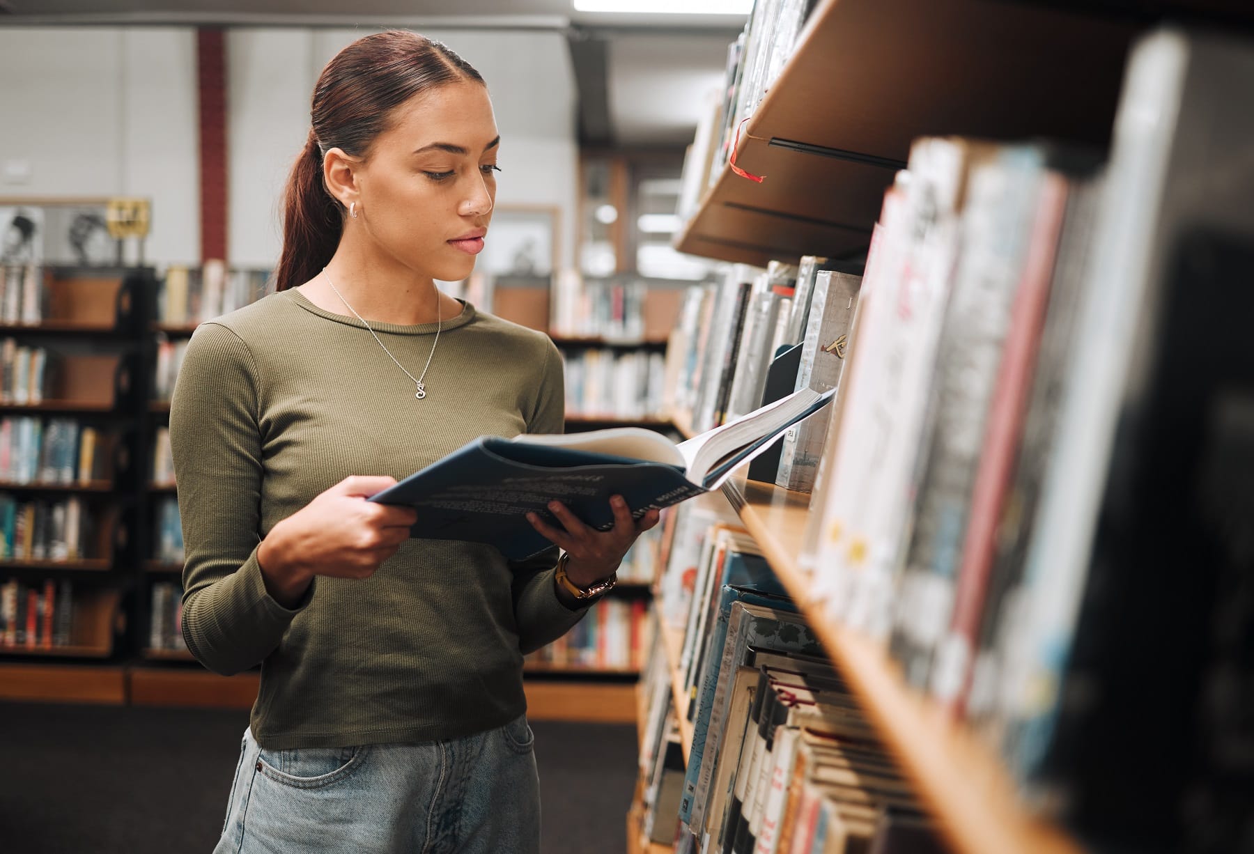 Junge Frau liest Buch in Bücherei