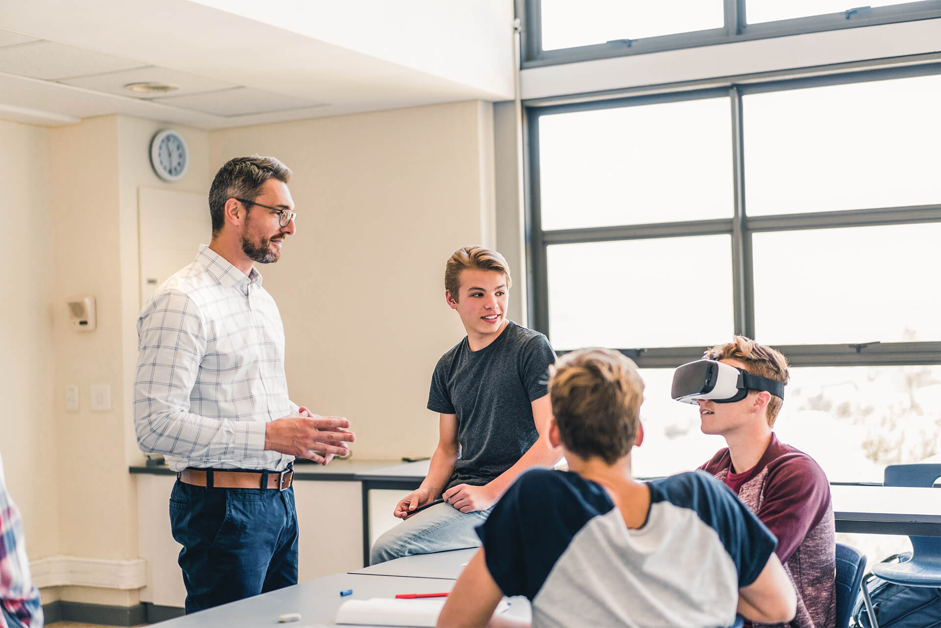 Lehrer probiert mit drei Jungs eine VR-Brille aus.