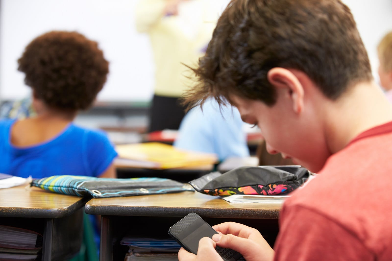 Schüler mit Smartphone in der Hand während des Unterrichts