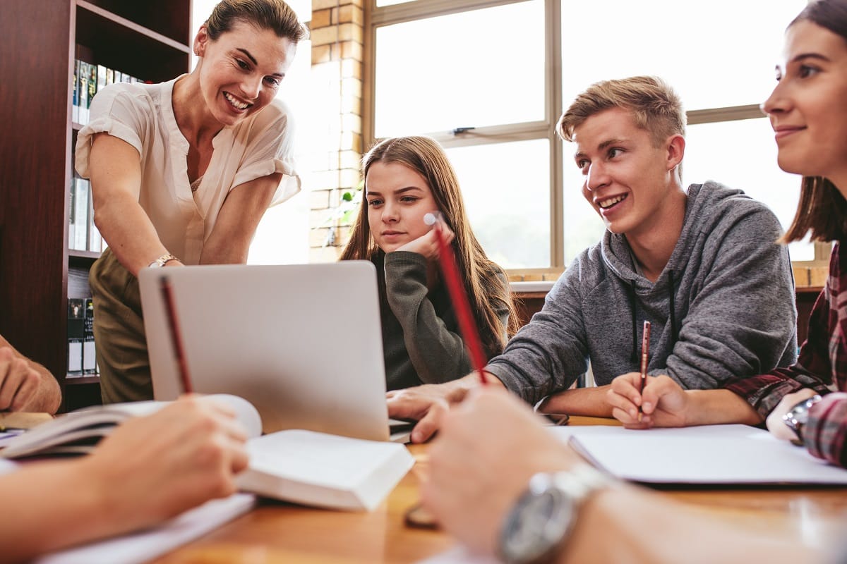 Lehrerin und Schüler schauen auf Laptop